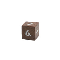 Close up of a single wood grain d6 die with white numbers on white