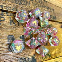 Set of colorful polyhedral dice with spider symbols on a wooden surface