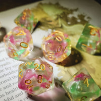Set of colorful polyhedral dice with floral design on a book page.