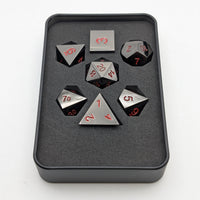 Set of metal dice with black and silver faces in a black box on a white background