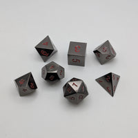 Set of metallic polyhedral dice with red numbers on a white background