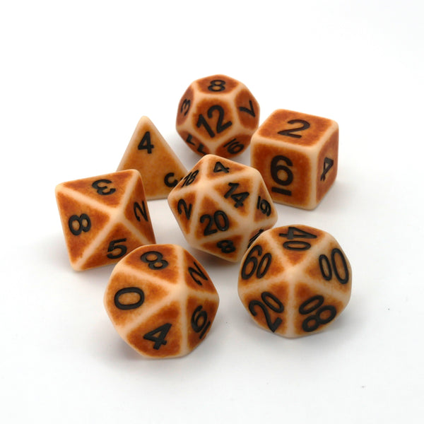 A set of seven polyhedral dice in a warm tan or light brown color with black printed numbers, arranged on a plain white background.
