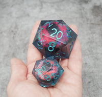 Two colorful polyhedral dice held in a hand against a gray background