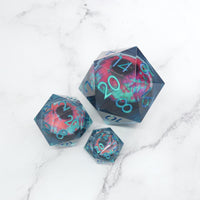 Three polyhedral dice with a blue and pink design on a marble surface