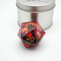 D20 polyhedral dice with red and black color scheme and gold numbers, placed in front of a metallic container.