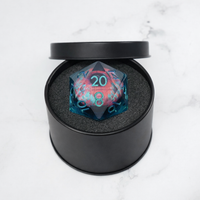 Translucent blue and pink polyhedral dice with numbers in a black round container on a light gray background